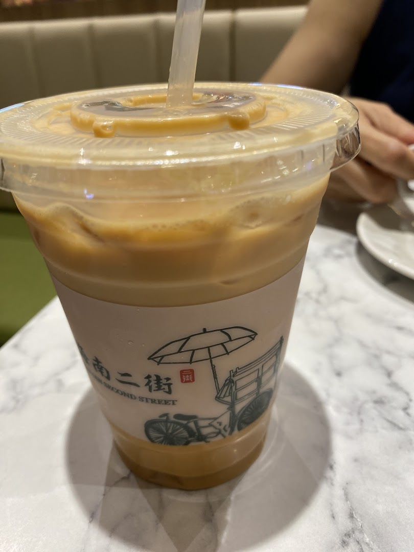 A plastic cup of iced beverage with a straw on a marble table.