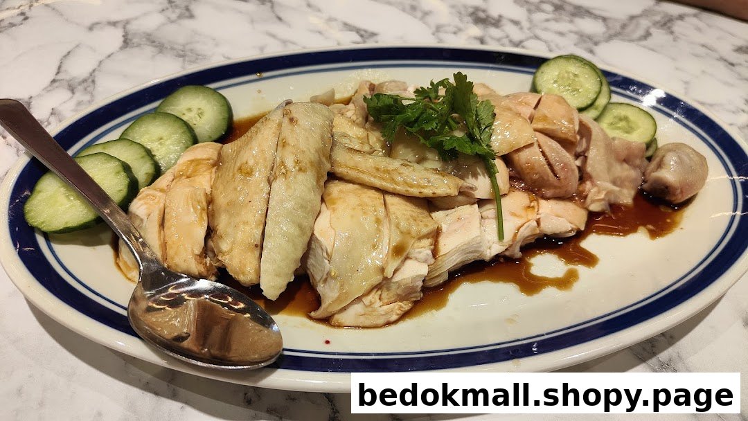 A plate of Hainanese chicken with cucumber slices and sauce.