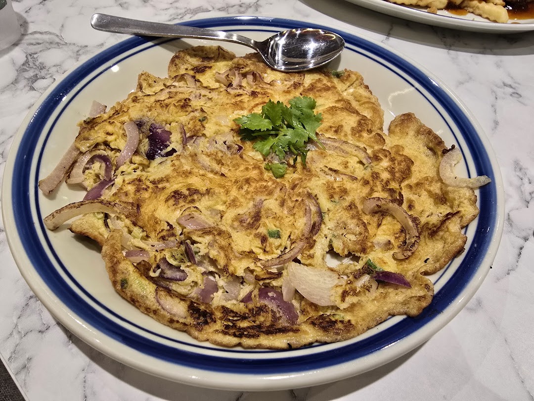A plate of omelet with onions and cilantro, served on a table.