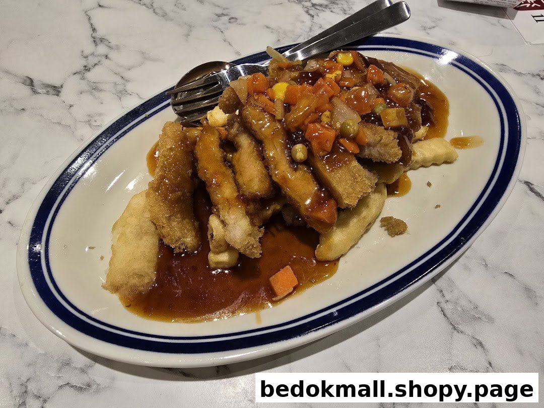 A plate of fried meat with sauce and mixed vegetables on a marble table.