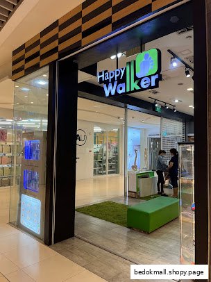 The storefront of Happy Walker with its sign, green mat, and two people inside.