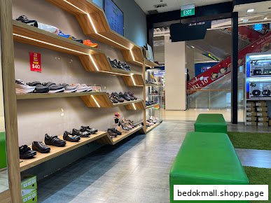 Interior view of a shoe shop with shoes displayed on shelves and green benches.