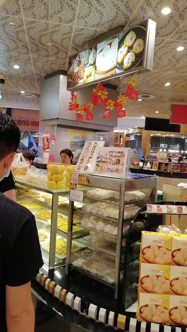 Interior of a food stall counter displaying dim sum and buns with staff.