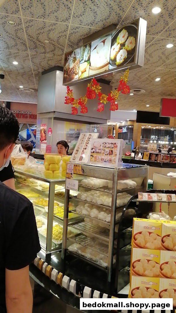Interior of a food stall counter displaying dim sum and buns with staff.