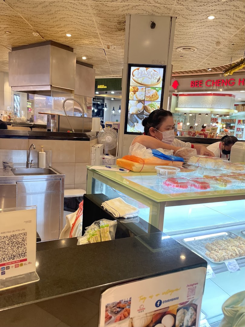 Staff working behind a counter with food displays in a shop interior.