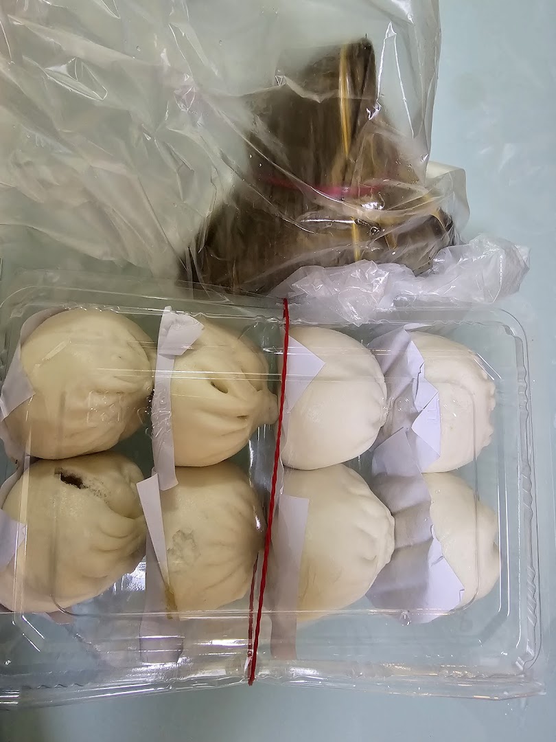 A plastic container of steamed buns and a wrapped food item in a bag.