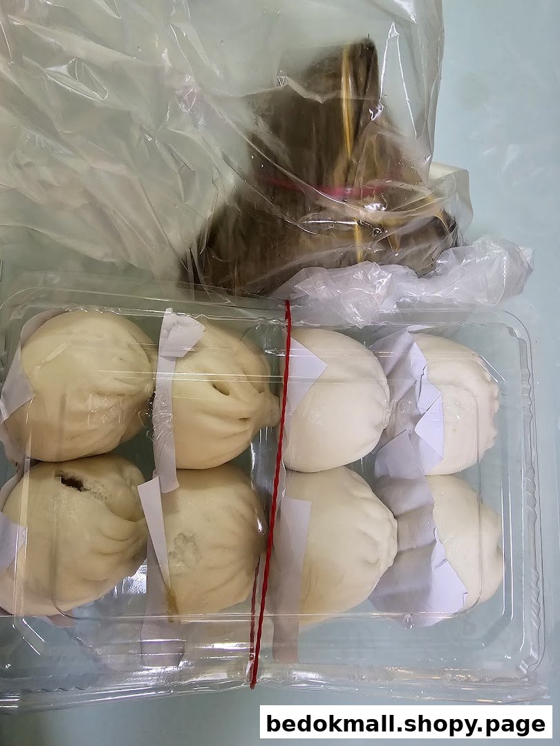 A plastic container of steamed buns and a wrapped food item in a bag.