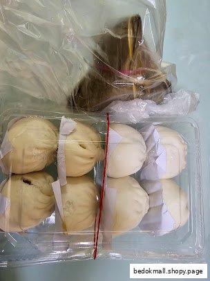 Steamed buns in a plastic container with another wrapped food item.