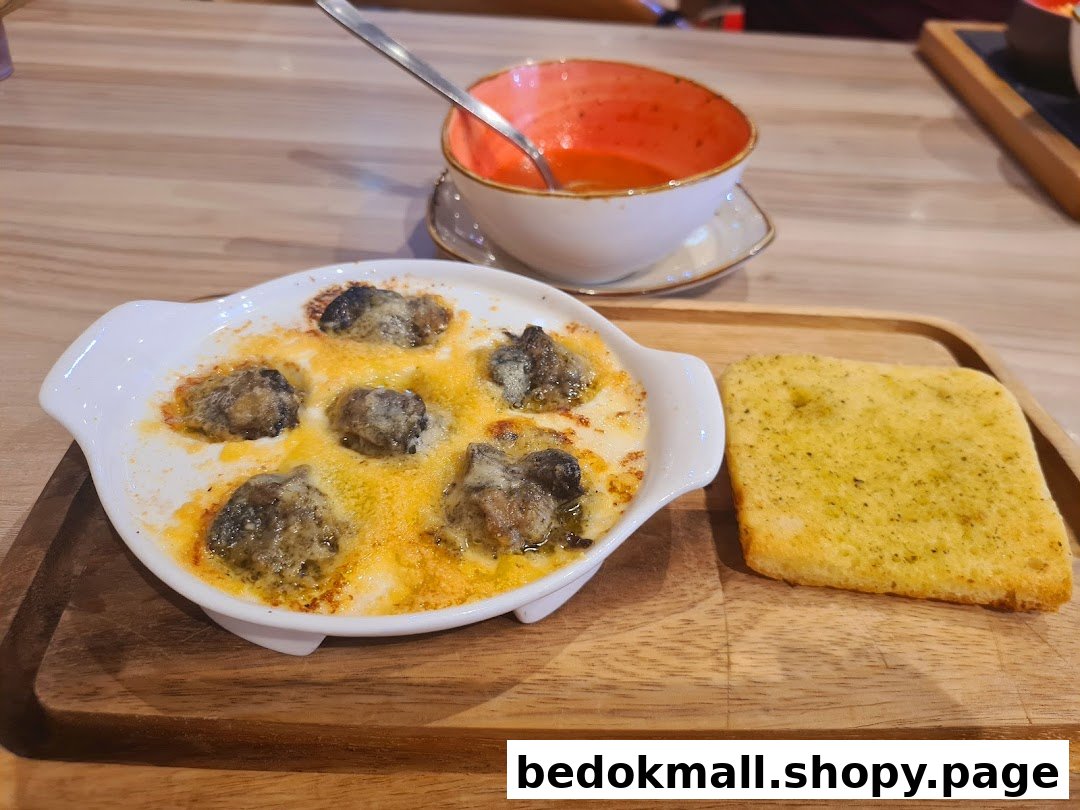 A dish of escargots, garlic bread, and soup on a wooden tray.