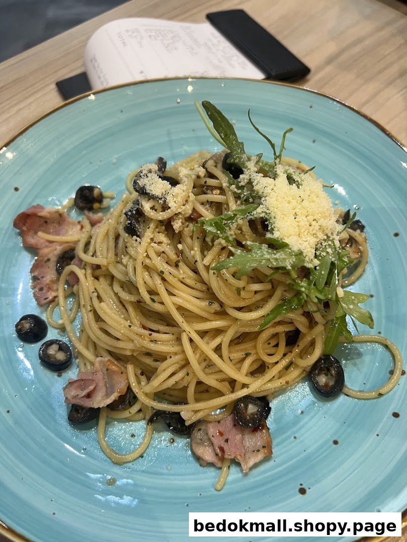 A plate of spaghetti with olives, bacon, cheese, and greens on a blue plate.