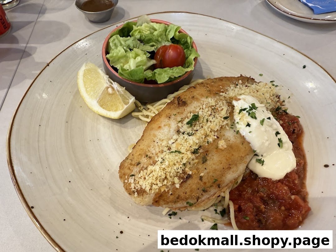 A plate of cooked fish with pasta, tomato sauce, salad, and a lemon wedge.