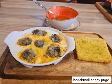 A dish of escargots with garlic bread and a bowl of soup.
