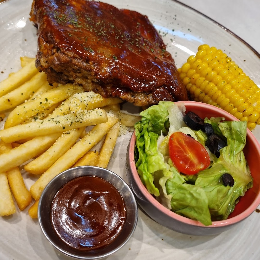 A plate of BBQ ribs with fries, corn on the cob, and a side salad.