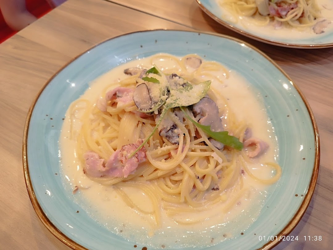 A plate of creamy pasta with mushrooms and bacon on a table.