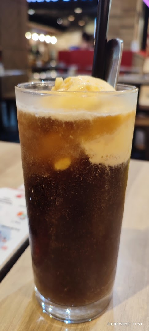 Close-up of a drink with ice cream and a straw in a glass.