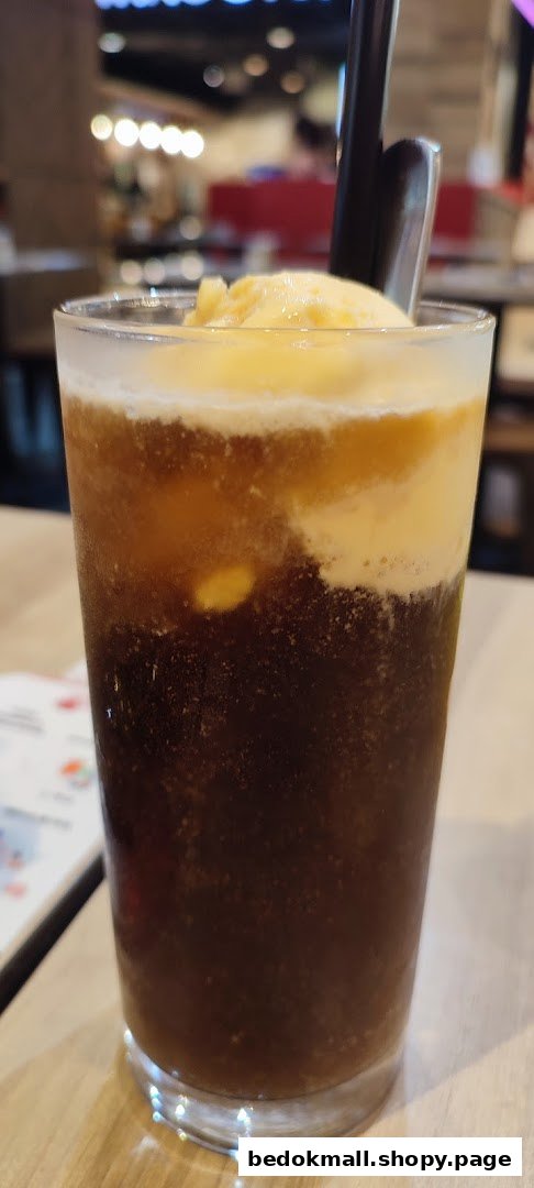 Close-up of a drink with ice cream and a straw in a glass.