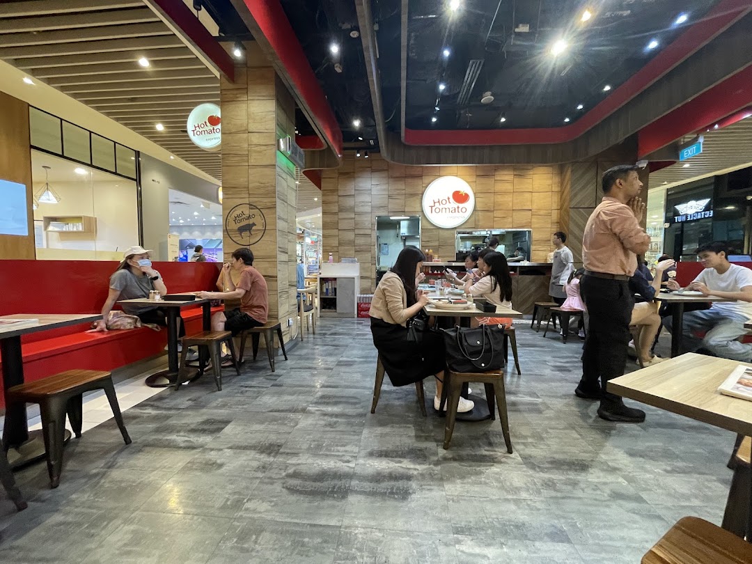 Customers dining inside a busy restaurant with red seating and wooden accents.