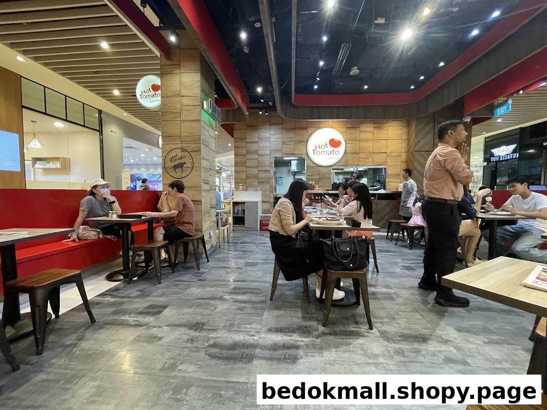 Customers dining inside a busy restaurant with red seating and wooden accents.