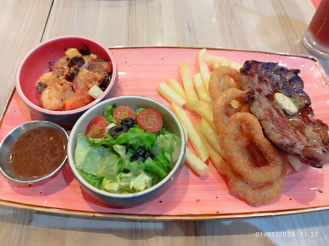 A plate with steak, fries, onion rings, salad, and seafood.