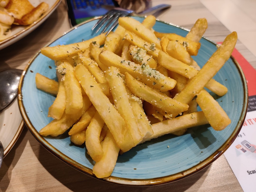 A blue bowl filled with french fries topped with herbs and cheese.