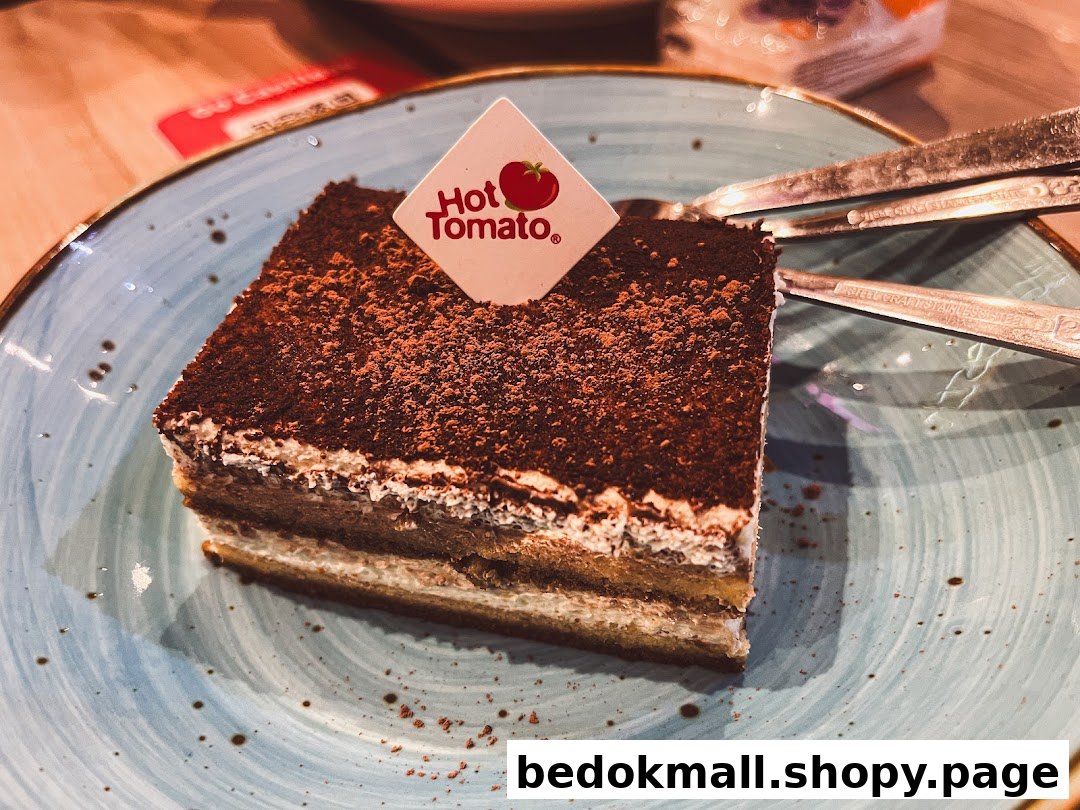A slice of chocolate-dusted cake with a Hot Tomato pick on a blue plate.