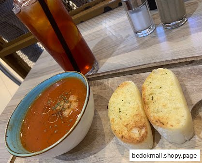 Tomato soup, garlic bread, and iced tea on a wooden table.