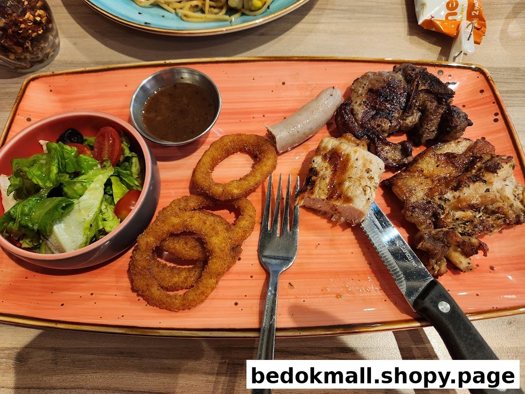 A plate with grilled meats, onion rings, salad, and sauce.
