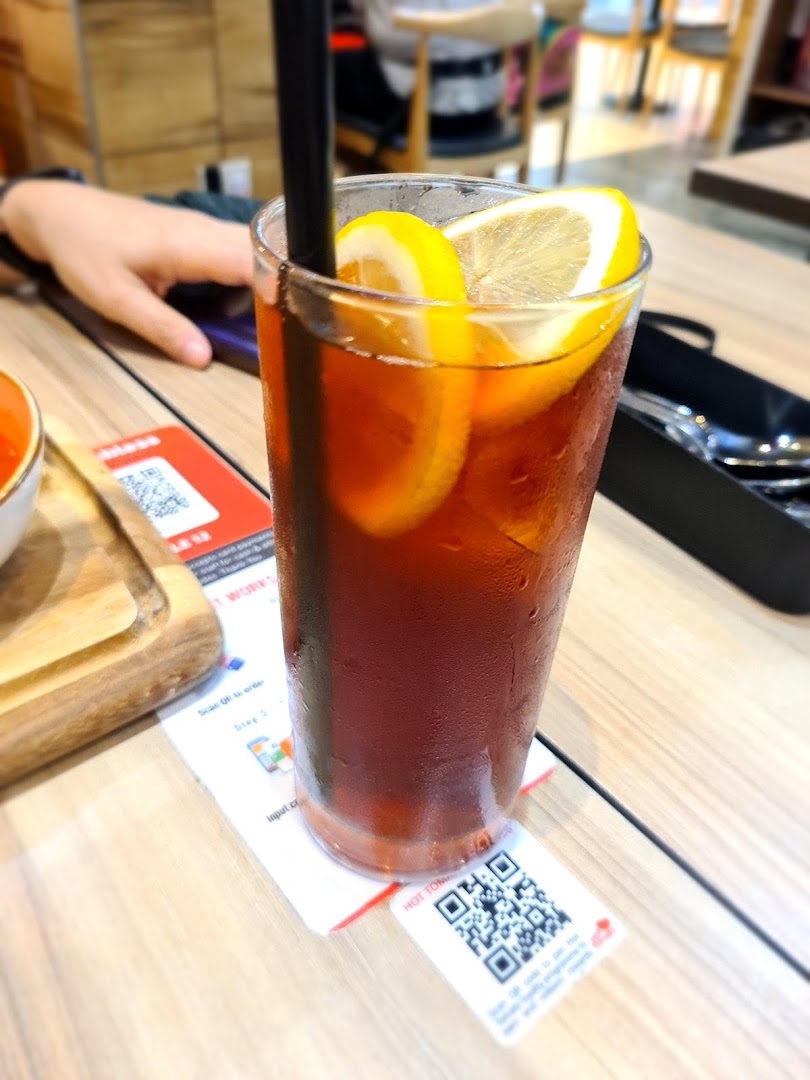 A glass of iced tea with lemon slices on a wooden table.