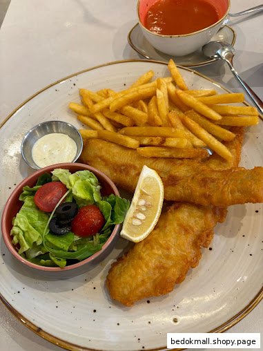 A plate of fish and chips with a side salad and a cup of soup.