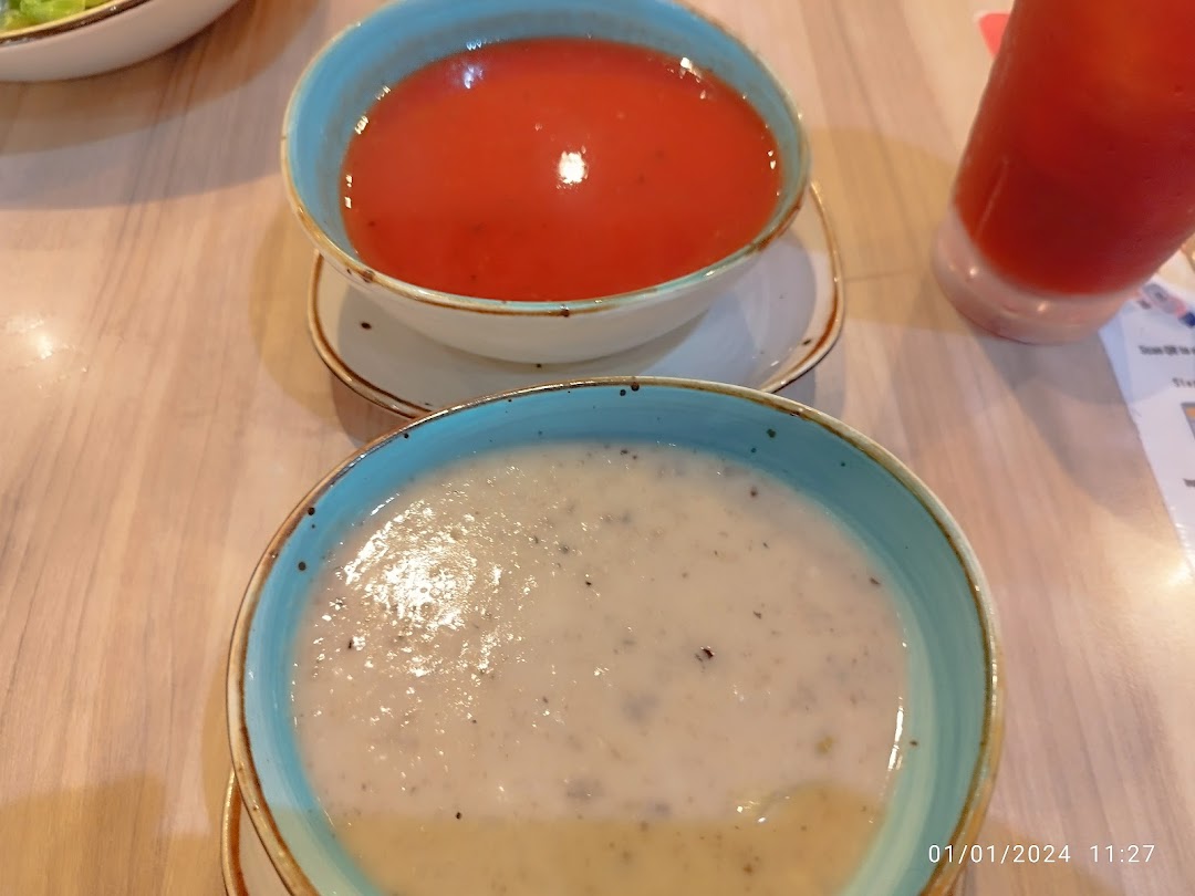 Two bowls of soup and a drink on a wooden table.