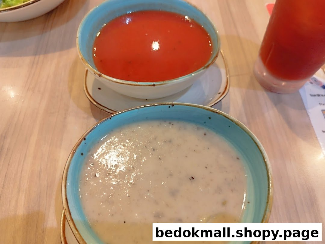 Two bowls of soup and a drink on a wooden table.