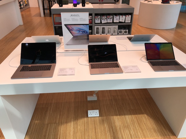 Laptops on display table inside a retail electronics store.