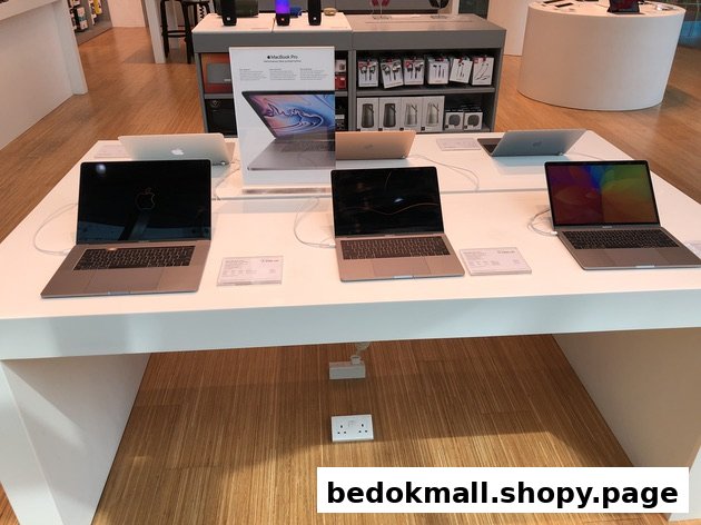 Laptops on display table inside a retail electronics store.