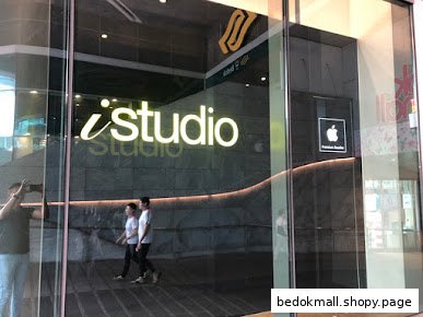 Glass shop front of iStudio with reflections and people walking by.