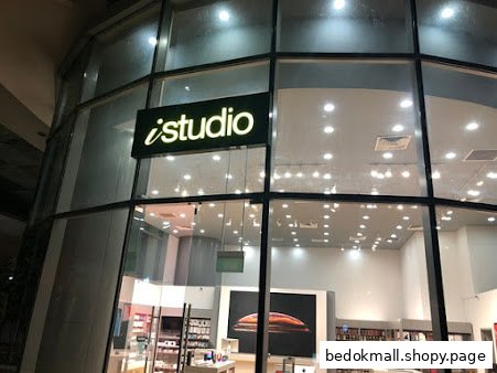 Exterior view of iStudio shop with large glass windows and visible interior.
