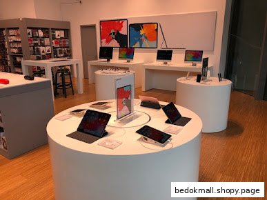 Interior view of an electronics store with display tables of devices and accessories.