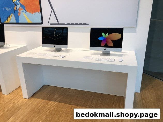 Two Apple iMac computers displayed on a white table in a retail store.