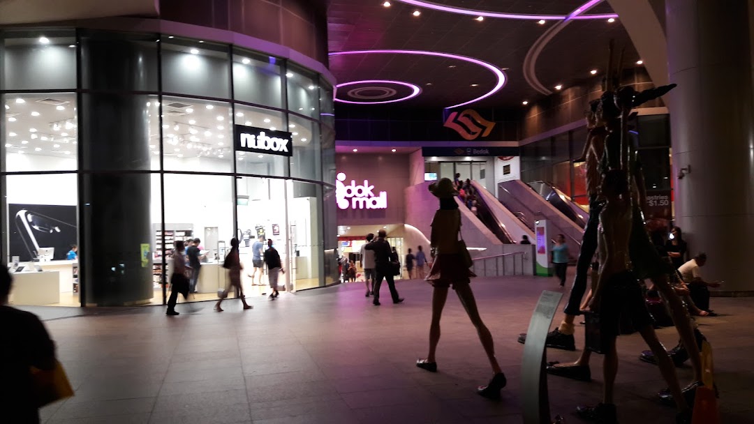 Exterior view of a brightly lit electronics shop with glass windows and people.