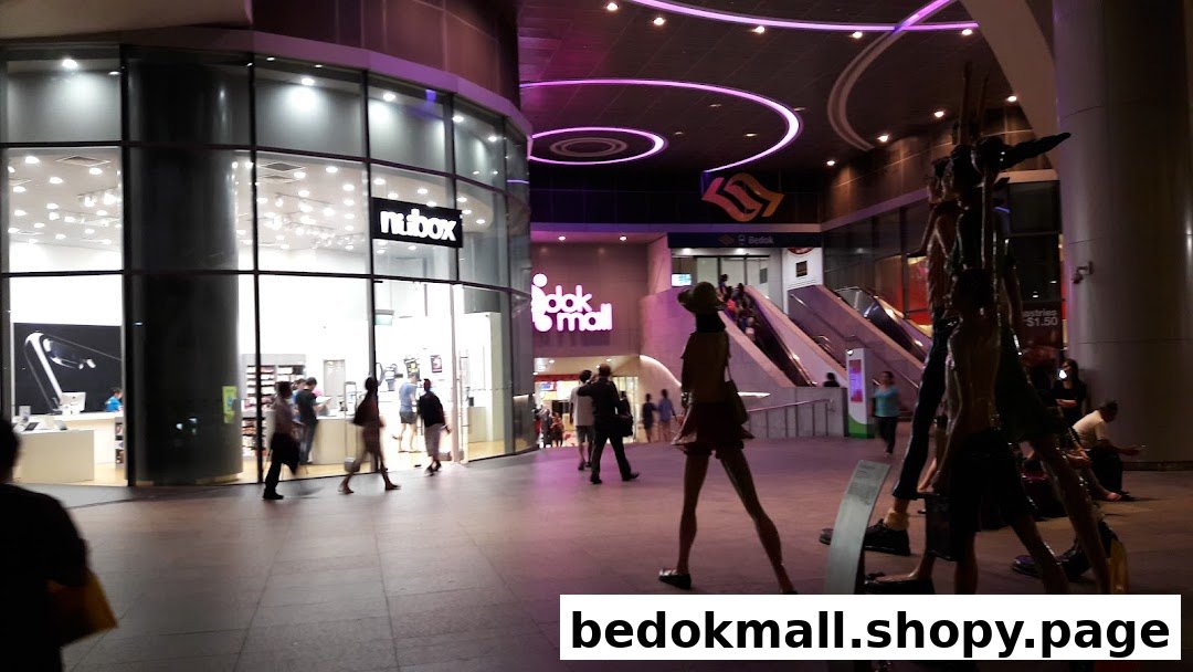 Exterior view of a brightly lit electronics shop with glass windows and people.