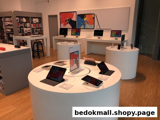 Electronics store interior with Apple products on display.
