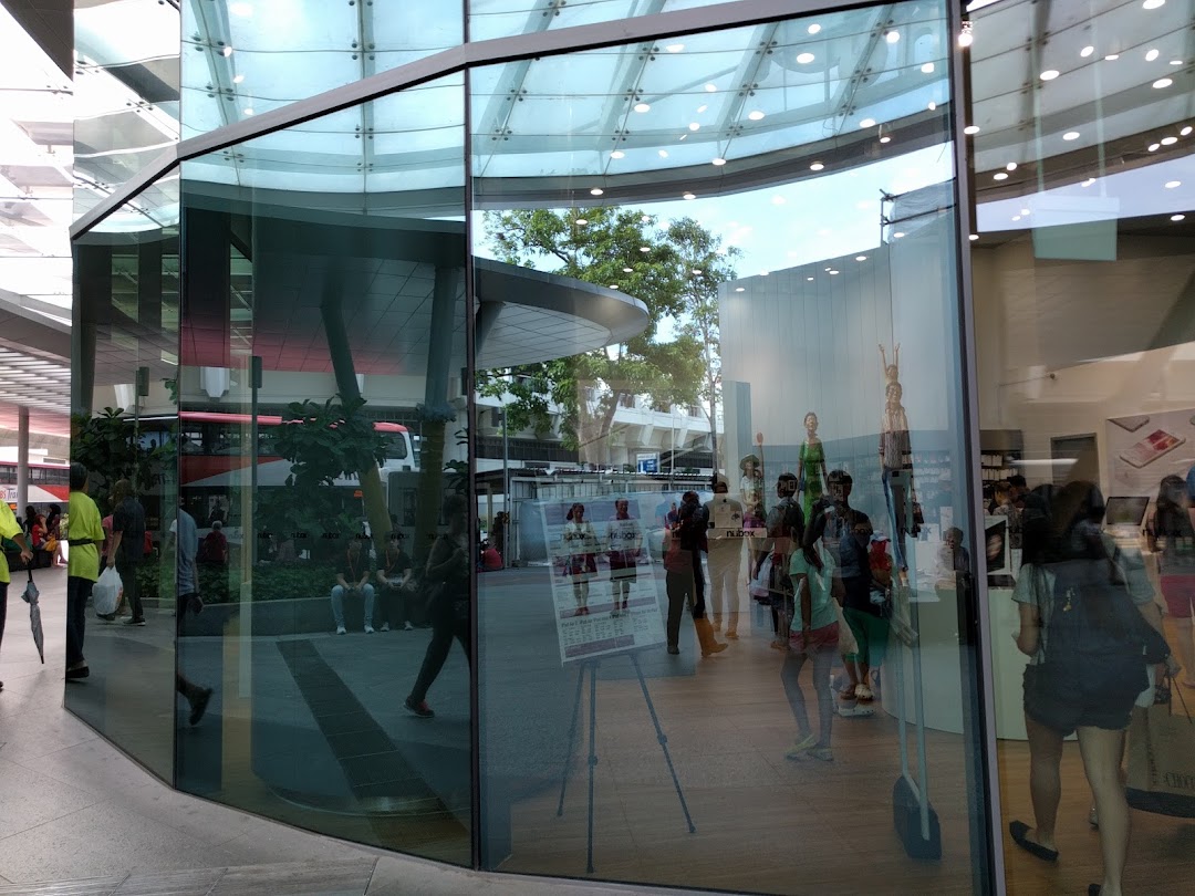 Glass shop front with reflections, showing interior and people outside.