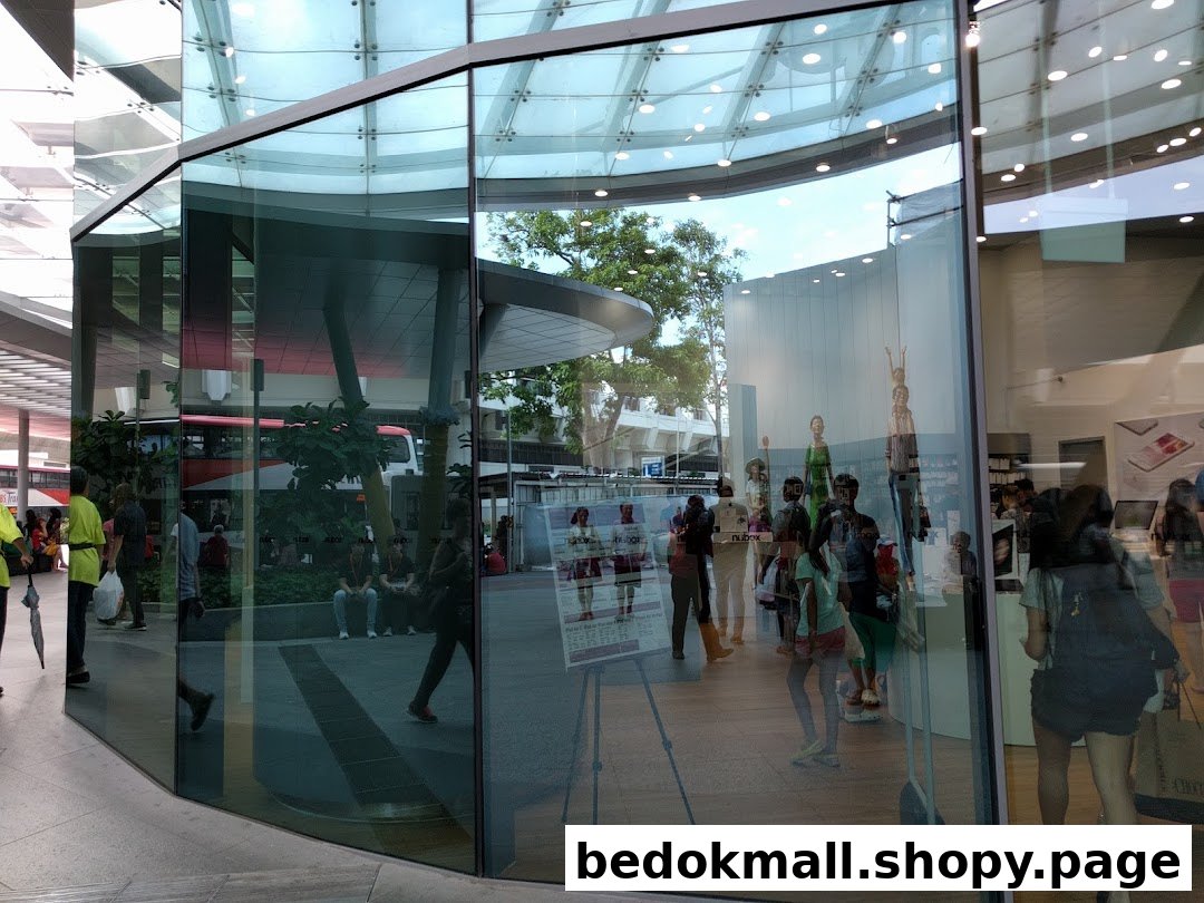 Glass shop front with reflections, showing interior and people outside.