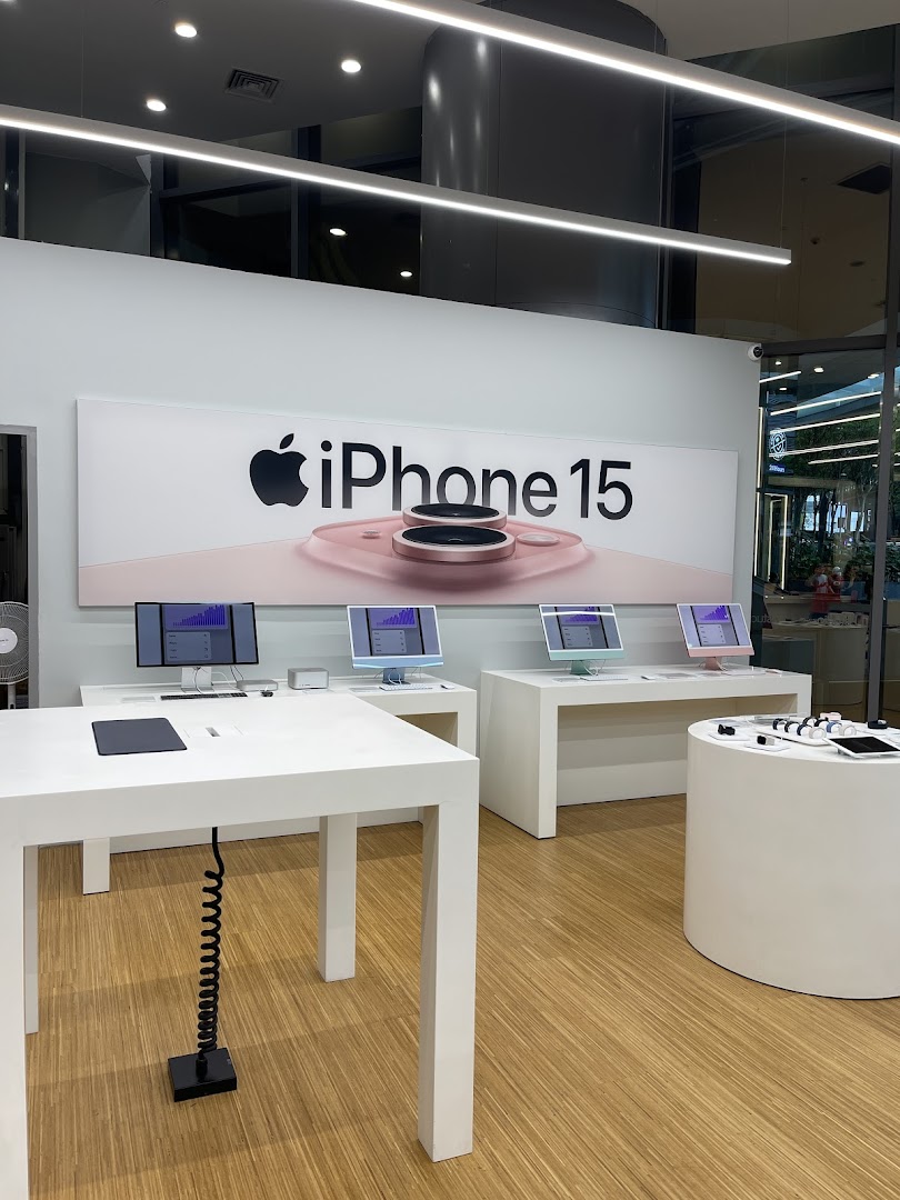 Interior of an electronics store with Apple products and an iPhone 15 banner.