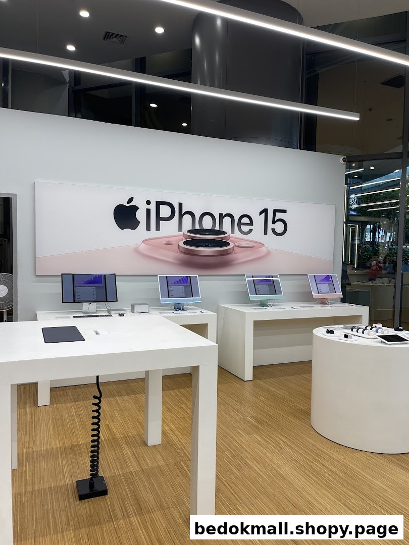 Interior of an electronics store with Apple products and an iPhone 15 banner.