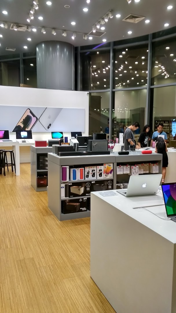 Interior view of an electronics store with display tables and customers browsing.