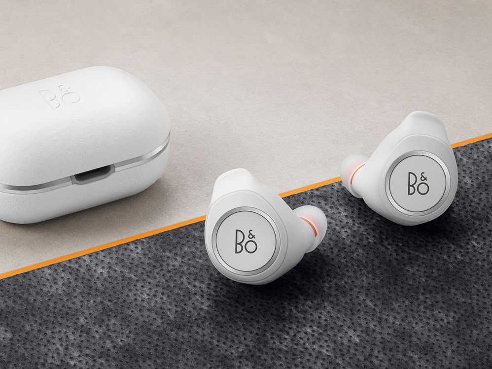 White wireless earbuds and their charging case on a textured surface.