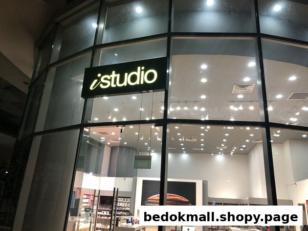 Illuminated 'iStudio' sign on a glass shop front at night.