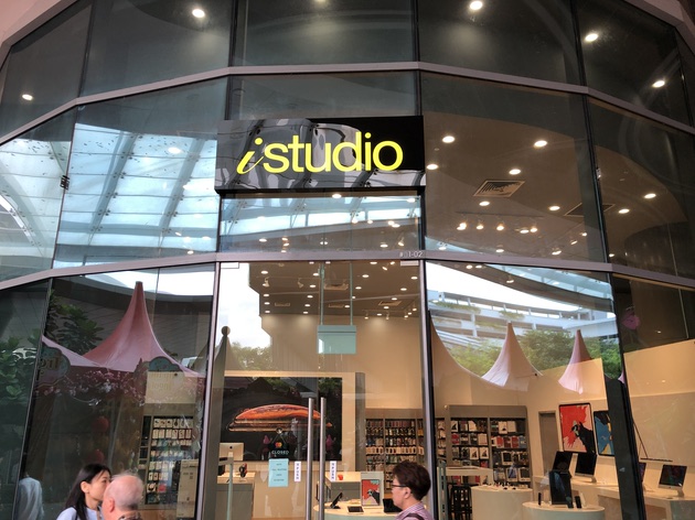 Glass facade of an iStudio shop with its prominent yellow logo and entrance.