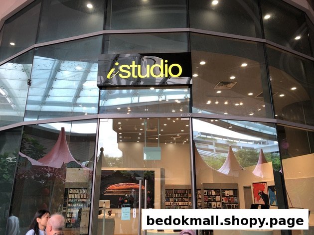 Glass facade of an iStudio shop with its prominent yellow logo and entrance.
