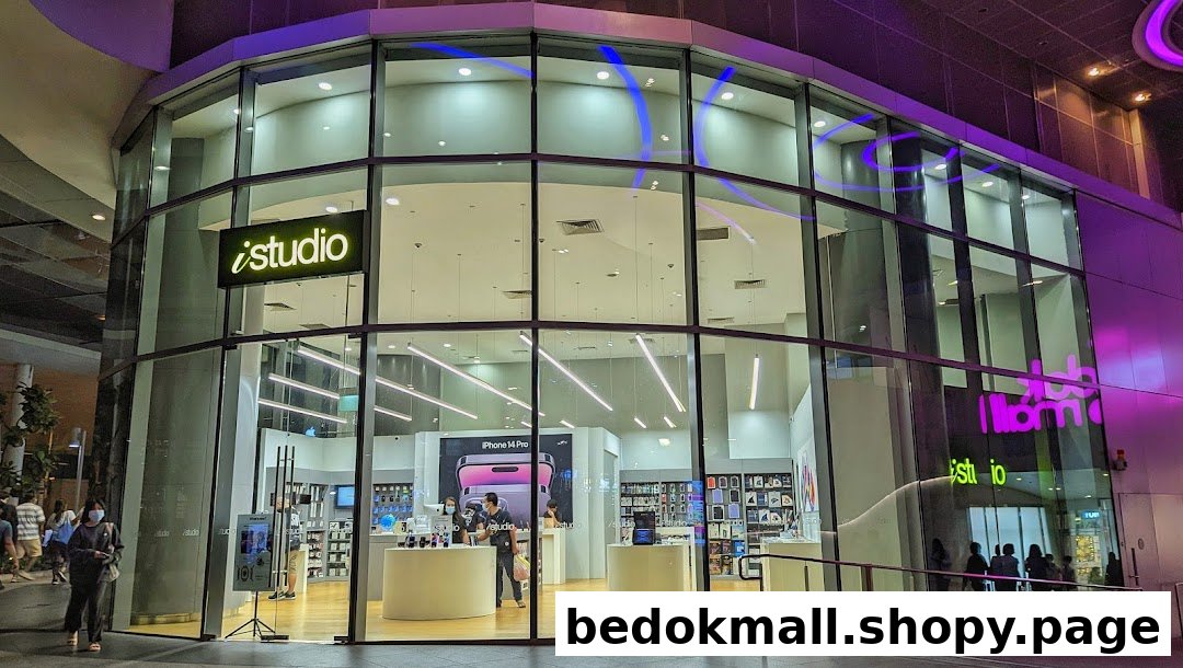 Exterior view of iStudio electronics store with large glass windows at night.